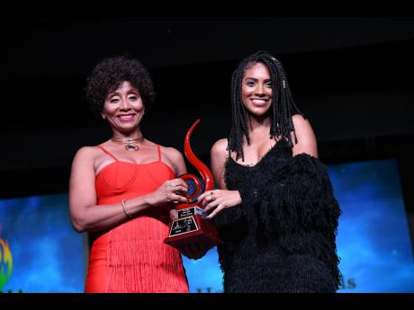 Naomi Cowan (right) receives the breakthrough artiste of the year award from Nadine Sutherland at the Jamaica Reggae Industry Association 2019 honours awards, held at the Little Theatre on Tuesday.