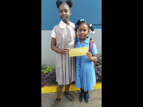 Credit: Daviot Kelly Gabrielle Gibson (left) hands over the money she saved to Brittannia Jones.
