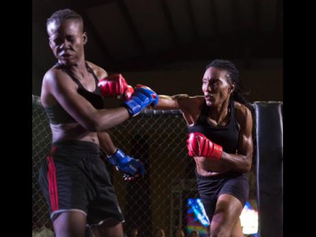 Shanice Blake (left) of Ruthless Sports Academy is left reeling after a hard right from Lisa Frazer, representing the Jamaica Defence Force (JDF) and Wushinkido Lion Pride Gym. The ladies competed for the female flyweight mixed martial arts championship at the Rough Fight League fight night held at the Douglas Orane Auditorium at Wolmer’s Boys School on Saturday, March 9. 