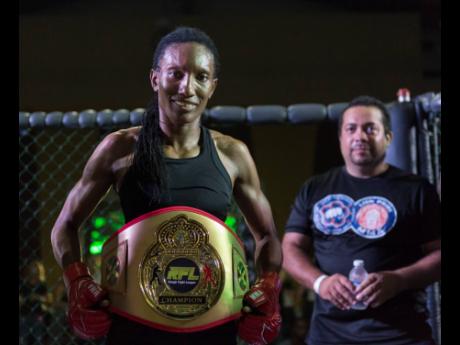 Frazer poses with her RFL Female Flyweight championship belt. Also pictured is Daniel Chacko-Wilmot (background), vice-president of Mixed Martial Arts Jamaica Sport. 