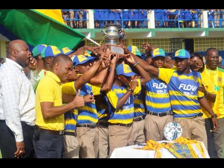 Then Rusea’s High School head coach Vassell Reynolds (right) joins in celebration with his players and their schoolmates after claiming the daCosta Cup trophy in the 2017 season.