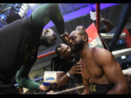 Sakima ‘ Mr Smooth’ Mullings (right) receives instructions from coach Chris Brown (centre) at the end of a round during a boxing match against Alejandro Herrera at the National Indoor Sports Centre, in Kingston, on Wednesday, July 25, 2018.
