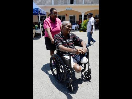 Alecia Salmon (left) assists wheelchair user Lancelot Harris at the Jamaica Health and Wellness Fair held at Lighthouse Assembly Church of God located in Spanish Town, St Catherine, last Friday.