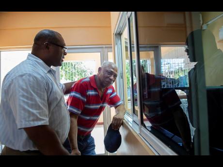Gladstone Taylor 
Following the murder of his daughter, Melford Clarke (right) is being consoled by Roy Notice, senior pastor at the Waltham Park New Testament Church of God on Waltham Park Road in St Andrew last week.