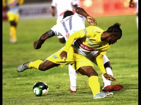Credit: Ricardo Makyn Waterhouse’s Kemar Beckford (front) goes up against Portmore’s Ewan Grandison in the final of the Red Stripe Premier League last year. Both teams will meet again tonight.