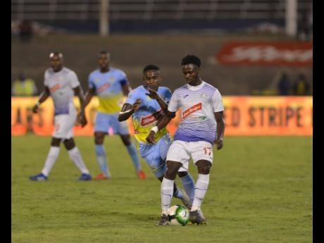 Portmore’s Andre Lewis shields Andre Leslie from the ball during second half of the Red Stripe Premier League on Monday night.