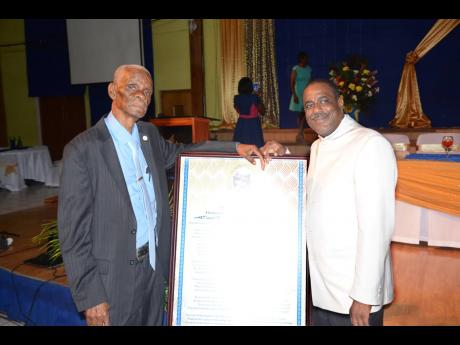 Alberga Foster (left) with Pastor Trevor Reid of the Orange Circuit of Seventh-day Adventist Churches in the West Jamaica Conference posing together with a citation that was given to Foster during a function held in his honour at the WJC Auditorium on May 5.