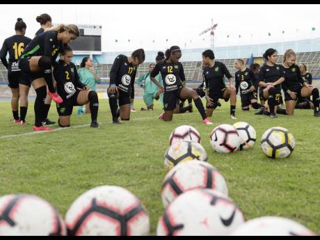 Members of Jamaica’s Reggae Girlz squad stretch before the start of a training session at the National Stadium.