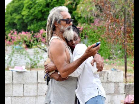 Actor and surfer Billy ‘Mystic’ Wilmot is comforted by his daughter-in-law, Janice Wilmot, after fire destroyed his home in Nine Miles, Bull Bay, St Andrew, yesterday. 