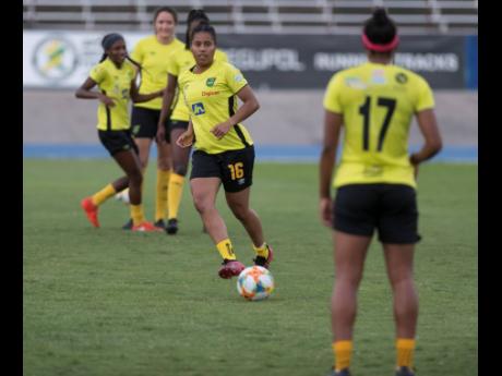 National defender Dominique Bond-Flasza (centre) makes a pass to teammate Allyson Swaby (right) during a training session at the National Stadium on Monday. The Reggae Girlz are preparing for an international friendly against Panama at the same venue on Sunday. 