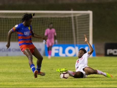 Credit: Gladstone Taylor Frantz Moise (left) of AS Capoise loses possession to Denilson Pierre of Real Hope FA, who put in a solid sliding tackle during their FLOW Concacaf Caribbean Club Championship game at Stadium East yesterday.