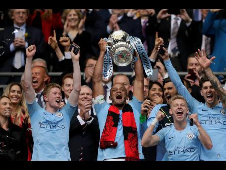 Manchester City’s team captain Vincent Kompany lifts the trophy after winning the English FA Cup Final between Manchester City and Watford at Wembley Stadium in London on Saturday, May 18. 