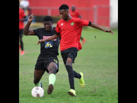 Jermaine Reid of Molynes United makes a challenge on  Lime Hall player Shaquill Wallace  in the JFF Premier league play-off at the  Constant Sprnng playing field on Sunday.