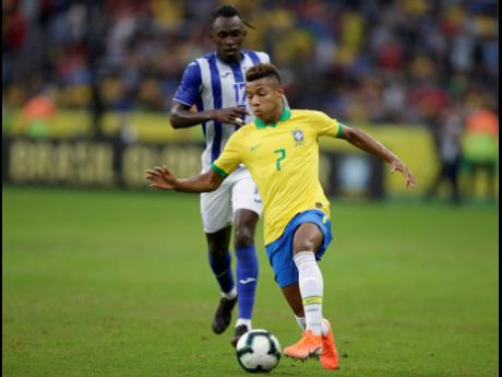 Brazil’s David Neres dribbles past Honduras’ Alberth Elis during a friendly match at the Beira Rio stadium in Porto Alegre, Brazil, on Sunday. 