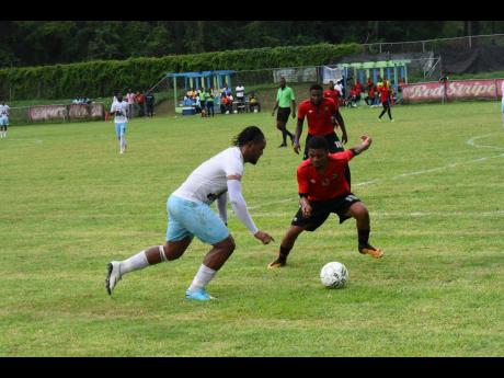 Peter Campbell of Faulkland FC dribbles by Kymani Gayle of Downs FC in their JFF Premier League play-off match at WesPow Park on Sunday, May 26, 2019. 