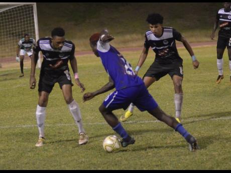 Reno’s Fancy-Hue Stewart (centre) drives forward while being closely marked by Cavalier’s Jamoi Topey (left) and his teammate Leonardo Rankine during their Red Stripe Premier League game at the Stadium East playing field last season.