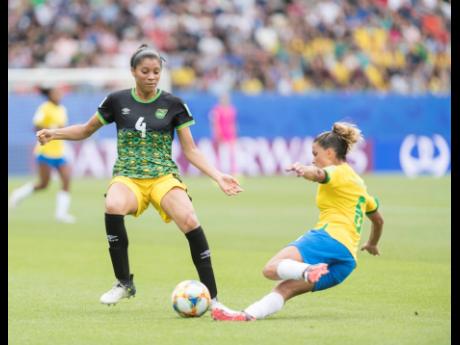 Chantelle Swaby (left) of Jamaica is tackled by Brazil’s Tamires Dias De Britto in Jamaica’s opening match at the FIFA Women’s World Cup 2019 at the Stade des Alpes in Grenoble, France, on Sunday.
