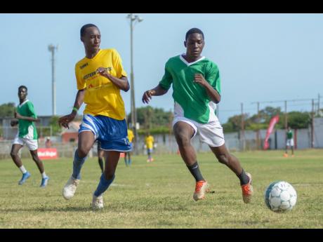 Blain Byam of Santos  (left) challenges Romario Campbell of Tivoli Gardens for a loose ball in the Under-17 match yesterday.