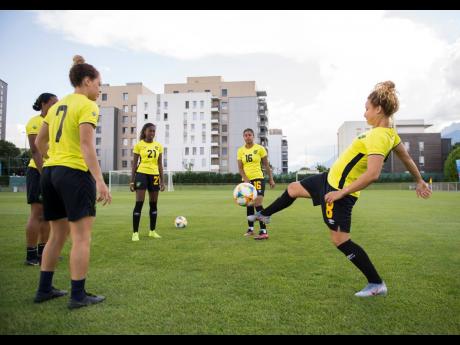 Allyson Swaby (obscured), Chinyelu Asher, Olufolasade Adamolekun, Dominique Bond-Flasza, and Ashleigh Shimm juggle the ball in a training session, yesterday at Stade Eugene Thenard in Grenoble, France.