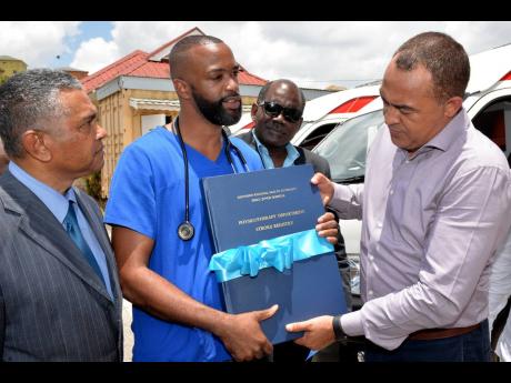 Roosevely Carty (second left), registered physical therapist at the Percy Junor Hospital, shows the new stroke registry to Health and Wellness Minister Dr Christopher Tufton (right) last Thursday. Sharing the moment are Michael Stern (left), deputy chairman of the Southern Regional Health Authority and Dr St Aubyn Bartlett, a member of the board.