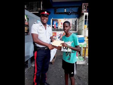 Constable Akeem Johnson (left) gives Jerome White money to buy sneakers after he finished 3k race while wearing flip-flops. 