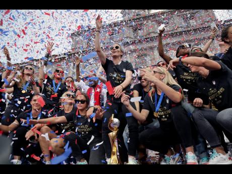 The US senior women's football team, and captain Megan Rapinoe (center), celebrate with the FIFA Women's World Cup trophy at City Hall after a ticker tape parade in New York City yesterday. (AP Photo/Seth Wenig)