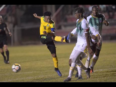 Jamaica’s Alex Marshall (left) shoots but his shot is blocked by Dominica defender Mitchel Gylles (centre) during their Caribbean Football Union Olympic Qualifying match at the Anthony Spaulding Sports Complex in Kingston last night. 