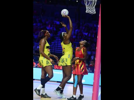 Jamaica captain Jhaniele Fowler (centre) shoots ahead of Uganda’s Muhayimina Namuwaya (right) as Romelda Aiken covers during their Vitality Netball World Cup game at the M&S Bank Arena in Liverpool, England, on Thursday. Photos courtesy of Collin Reid, Courts Jamaica, Jamaica Tourist Board, Alliance Investments, Dairy Industries, and Supreme Ventures.