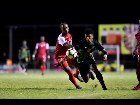 Jamaica’s Nicque Daley (right) on the attack as Salas Cannonier of St Kitts and Nevis looks on  at the Anthony Spaulding Sports Complex yesterday.