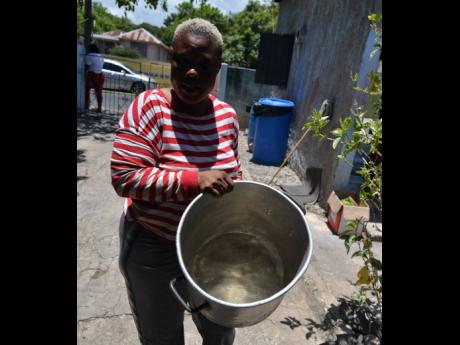 A resident
from Rosalee Ave
in the Kingston 11
area shows a pot that
she uses to carry water.