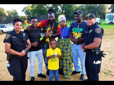 Two East Orange police officers welcome Jamaica’s ‘Hold Yuh Position’ artiste Don Reid (second left) to the Orange Carnival in New Jersey last Saturday. Third from left is New Jersey  deejay Ras Emmanuel.