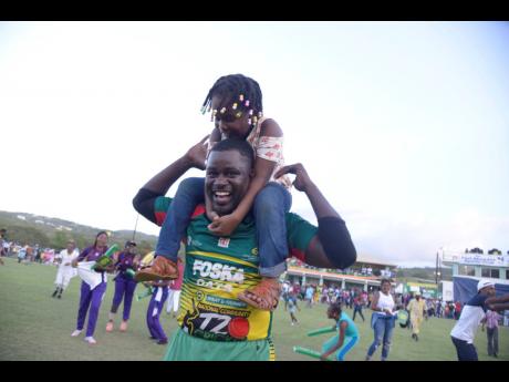Gayle Cricket Club’s Mickail Downer celebrates with his daughter  Mahelea after winning the SDC/Wray & Nephew community 
cricket final yesterday.
