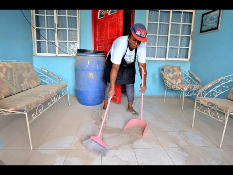 Sharon Lindsay sweeps dust from the balcony of her house in Majesty Gardens, St Andrew, yesterday.
