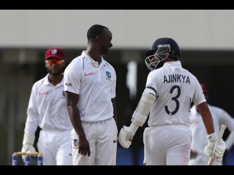 West Indies bowler Kemar Roach (centre) and India’s Ajinkya Rahane talk during day three of the first Test cricket match at the Sir Vivian Richards cricket ground in North Sound, Antigua and Barbuda, on Saturday, August 24, 2019. 