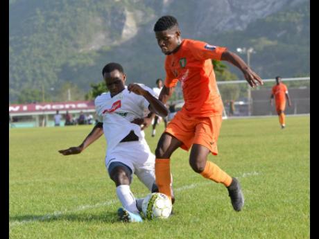 Credit: Kenyon Hemans UWI FC’s Andre Humphrey (right) tackles Junior McGregor of Tivoli Garden in their Red Stripe Premier League opener yesterday.