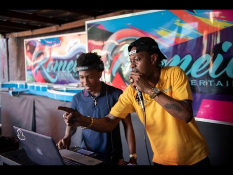 Ace selector  Bishop Escobar (right) and DJ Deva Kid vibing at the turntables during an interview session at Romeich’s studio in St Andrew on Friday.