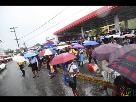Commuters are stranded in the rain on North Odeon Avenue yesterday due to the withdrawal of services by drivers of the Jamaica Urban Transit Company.