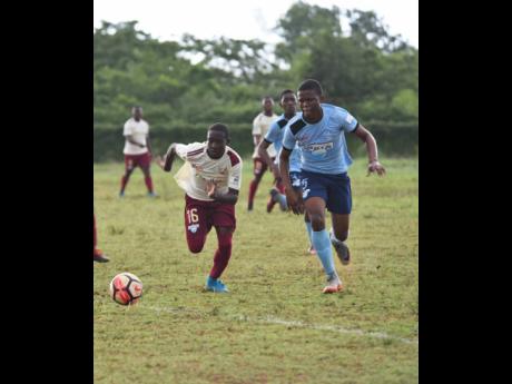 Herbert Morrison Technical High School's Marc Graham (left) races Holland High School's Demar Chambers to collect the ball in their ISSA/WATA DaCosta Cup game at the Holland High School Field on Monday, October 8, 2018.