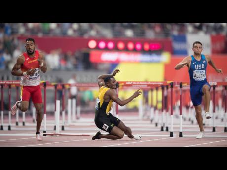 Jamaica’s Omar McLeod goes down during the men’s 110m hurdles  final at the 2019 IAAF World Championships in Doha, Qatar, yesterday. McLeod was later disqualified for  impeding  Spanish athlete Orlando Ortega (left). 