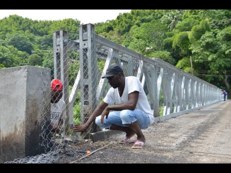 Kenyon Hemans/Photographer
Garfield Edward (partially hidden) and Withman Hunt fasten a  fence along the sides of  the newly built Chesterfield Bridge in St Mary. 