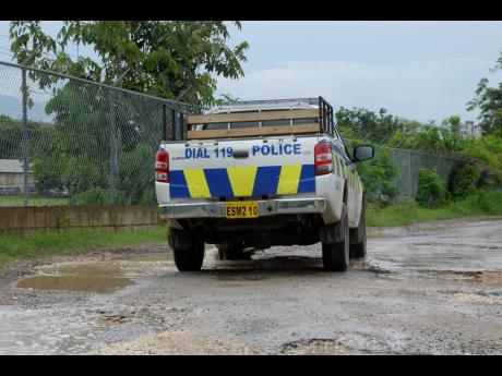 A police service vehicle manoeuvre the pothole-filled road.