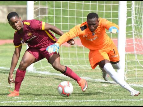 Tarrant High goalkeeper Jonathan Currie (right) getting to the ball ahead of  Zhavier Lynch of  Wolmer’s Boys during yesterday’s ISSA/Digicel Manning Cup match at the  Stadium East field. Wolmer’s won 3-0.