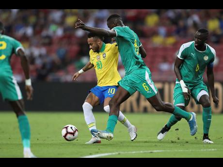 Brazil’s Neymar (centre) and Senegal’s Salif Sane in action during the Brazil Global Tour 2019 international friendly in Singapore yesterday. The match ended 1-1.