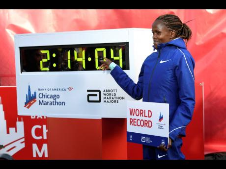 Brigid Kosgei of Kenya poses with her time after breaking the world record with a time of 2:14:04 during the Chicago Marathon yesterday.