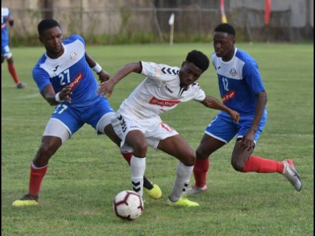 Trey Bennett (centre) from UWI FC tries to go between the Portmore United pair of Sheldon McKoy (left) and Venton Evans (right) during their Red Stripe Premier League football match  at the Spanish Town Prison Oval yesterday.