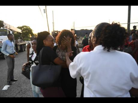 A vice-principal (centre) of Clan Carthy Primary School is consoled after the accident that took the life of Seymour Benjamin.
