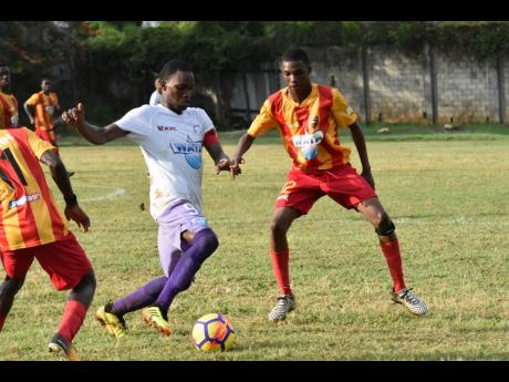 Andre Tate of Irwin High School (centre) tries to dribble past Calvin Gardener of Cornwall College in their  ISSA/WATA daCosta Cup encounter at the Cornwall playing field in Montego Bay last season.