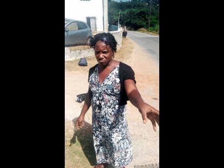 Claudette Jarrett shows the cuts and bruises she received from her son outside the Yahweh compound in St James.
