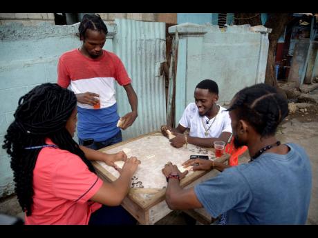 LaaLee (second right) enjoying a game of dominoes with STAR reporter Shereita Grizzle (left) and his friends.