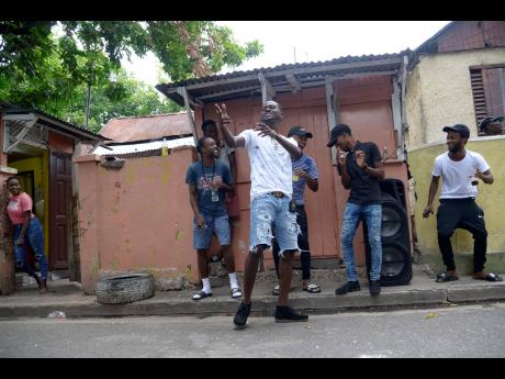 TOP PHOTO: LaaLee (centre, foreground) clowns around with his friend on Septimus Street, in his native Jones Town.